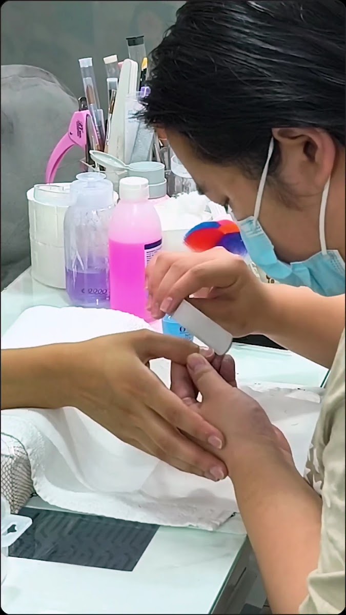 Una manicurista limando las uñas de una clienta